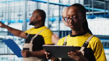 Sanayi 4.0 bitki teknisyeni dijital cihaz uygulaması kullanılarak sistem performansını izliyor. Akıllı fabrika mühendisi, tablet, kamera A 'daki yazılımı kullanarak robotik silah ve taşıma bantlarının çalışmasını denetliyor.