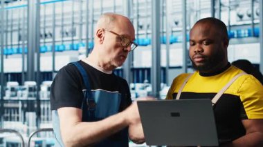 Fotovoltaik zeki fabrika lideri stajyere bilgisayarla hasar görmüş IOT sensörlerini nasıl onaracağını öğretiyor. Endüstri 4.0 güneş panelleri. Bitki fabrikası, stajı azaltma konusunda tecrübeli mühendis rehberi, kamera A