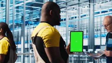 Akıllı fabrikada yeşil ekran dizüstü bilgisayar kullanan işçiler veri toplayıp analiz ediyorlar. Gelişmiş sensörlerle donatılmış endüstriyel tesiste krom anahtar defteri üzerinde izleme yazılımı kullanan uzman, kamera A