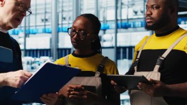 Akıllı fabrika lideri tesisin zeminindeki robotik silah operasyonunu denetleyen çalışanlarla konuşuyor. Endüstri 4.0 fabrika işçileri, sorun çıkarılan hatalar hakkında beyin fırtınası yapıyorlar, kamera A