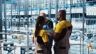 Endüstri 4.0 endüstriyel fabrika mühendisliği ekibi tablet üzerinde CAD uygulaması kullanarak yeni robotik makineler tasarlıyor. Takım çalışması akıllı fabrika çalışanları otomasyon ekipmanları programlıyorlar, kamera A