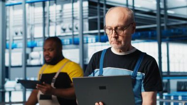 4.0 endüstriyel fabrika kıdemli mühendisi dizüstü bilgisayar yazılımı kullanarak robot makineleri otomatikleştiriyor. Deneyimli teknisyen akıllı fabrikada yapay zeka özelliklerini not defteri, kamera A kullanarak uyguluyor.