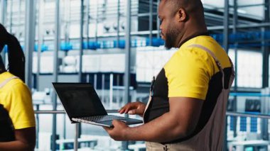 Endüstri 4.0 endüstriyel fabrika uzmanı dizüstü bilgisayarda CAD yazılımı kullanarak yeni robotik makineler tasarlıyor. Otomasyon ekipmanları için dizüstü bilgisayar kullanan akıllı bir fabrika teknisyeni.