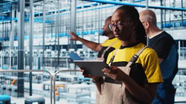 Sanayi 4.0 bitki teknisyeni dijital cihaz uygulaması kullanılarak sistem performansını izliyor. Akıllı fabrika mühendisi, tablet, kamera A 'daki yazılımı kullanarak robotik silah ve taşıma bantlarının çalışmasını denetliyor.