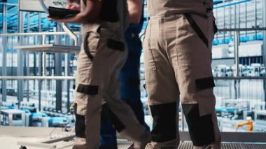 Sanayi 4.0 fotovoltaik fabrikası mühendisi güneş pillerinin enerji üretimini maksimuma çıkarmak için tablet üzerinde yazılım kullanıyor. Güneş panellerini denetleyen Afrikalı Amerikalı adam akıllı fabrika ekipmanları, kamera A