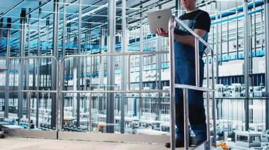 Endüstri 4.0 endüstriyel fabrika uzmanı robot üretim makinelerini cihaz kullanarak otomatikleştiriyor. Not defteri ve kamera A kullanarak akıllı fabrikada yapay zeka uygulayan yaşlı bir çalışan.