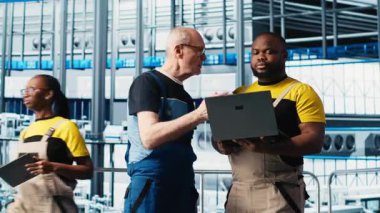 Akıllı fotovoltaik fabrikasındaki kıdemli mühendis stajerle konuşuyor, sistem performans ölçümlerini gösteriyor. Deneyimli güneş panelleri enerji üretimini takip eden yeni stajyer ve kamera A 'ya rehberlik ediyor.