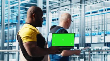 Makineleri kurmak için 4.0 endüstriyel santralde yeşil ekran dizüstü bilgisayar kullanan bir mühendis. Robot teknisyenleri akıllı fabrika sensörlerini ayarlayan, çekim yapan akıllı bir not defteri kullanıyorlar.