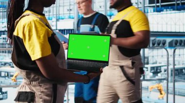 Akıllı bir fabrika teknisyeni robot kolları kontrol ediyor. Model defter kullanarak, kapat. Sektör 4.0 endüstriyel santraldeki mühendis otomatik makineleri yeşil ekran dizüstü bilgisayar ve kamera A kullanarak kontrol ediyor.