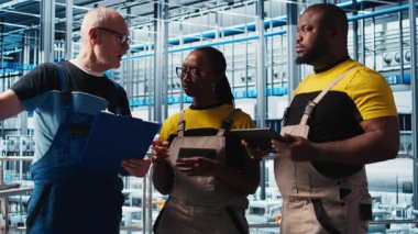 Akıllı fabrika lideri tesisin zeminindeki robotik silah operasyonunu denetleyen çalışanlarla konuşuyor. Endüstri 4.0 fabrika işçileri, sorun çıkarılan hatalar hakkında beyin fırtınası yapıyorlar, kamera A