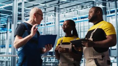 Sanayi 4.0 fotovoltaik tesisi kıdemli mühendis, işçilerle güç üretimini en üst seviyeye çıkarmak için evrak görüşmeleri yapıyor. Güneş panelleri akıllı fabrika tecrübeli liderleri teknisyenlere ve kamera A 'ya görev veriyor.