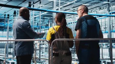 CAD yazılımında üretim hatları tasarlayan fotovoltaik akıllı fabrika işçilerini denetleyen yönetici. Sanayi 4.0 güneş panelleri fabrika ekip lideri kat planlarını optimize eden çalışanları denetliyor, kamera A
