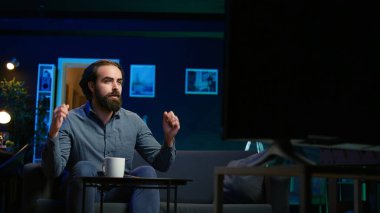 Taraftarlar oturma odasında canlı yayında spor izliyorlar. En sevdikleri takımı kaybederken acı çekiyorlar. Kalbi kırık destekçi evde enerjik el hareketi yapıyor, kaçırılan şanslardan rahatsız oluyor, kamera B