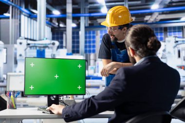 Photovoltaics fabrikasındaki iş arkadaşları, model PC kullanarak üretim akışını optimize etmek için beyin fırtınası yapıyorlar. Güneş panelleri fabrika uzmanları yeşil ekran bilgisayarda üretim sürecini izliyorlar