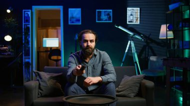 Sıkıcı insan TV karşısında kanepede abonelik temelli yayın yapan uzaktan kumandayla gezinen. Yorgun adam TV 'de VOD programları izliyor, Kanallara çarpıyor, Kamera B