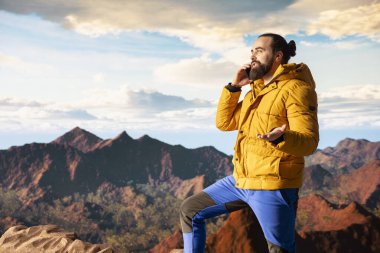 Trekker yüksek rakımlı manzaranın tadını çıkarıyor ve bir telefon görüşmesi yapıyor, panoramik dağ manzarası ve gevşek hava rahatlama için mükemmel bir manzara sağlıyor. Akıllı telefonunda güçlü bir sinyal kullanıyor..