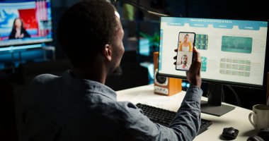 Danışmanlarla görüntülü konuşma yapan siyahi ekonomist, kazanç dengesi analizi ve potansiyel büyüme için mali dalgalanmayı izliyor. Uzman iş arkadaşlarıyla tartışıyor. Kamera A.