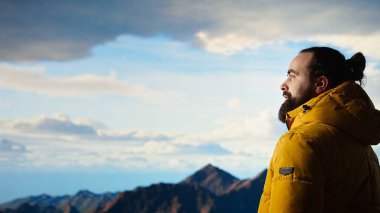 Yürüyüşçü dağların panoramik manzarasına hayran olmak için bir dakikasını ayırır, uzaklığa ve manzaraya bakar. Temiz hava, manzaralı arka plan ve bir kaşif için huzurlu bir ortam. Kamera A.
