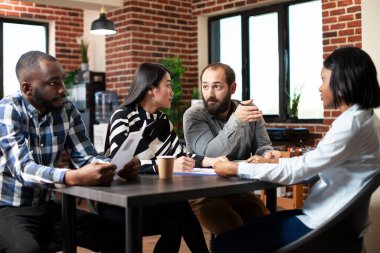 Çeşitli üye alma grupları potansiyel kadın çalışanları değerlendiriyor, iş görüşmeleri sırasında deneyim hakkında sorular soruyorlar. Asyalı kadın ve beyaz adam genç siyahi bir kadını işe alma konusunda fikir alışverişinde bulunuyorlar..