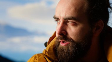 Tatmin olmuş maceracı, dağın zirvesinde kişisel başarısını kutluyor, nefes alıyor ve zirvede manzaranın tadını çıkarıyor. Macera ve açık hava keşfi için motivasyon. Kamera B.