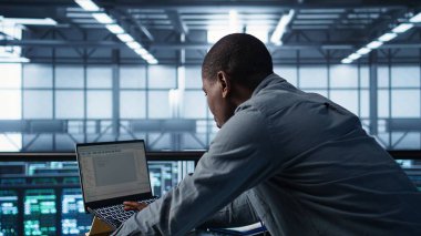 Veri merkezinde bilgisayar kullanan, güç yönetimi ayarlarını ayarlayan, programlama dilleri kullanan bir teknisyen. Sunucu odasındaki adam kaynak kullanımını optimize eder, istikrarlı altyapıyı korur, kamera B