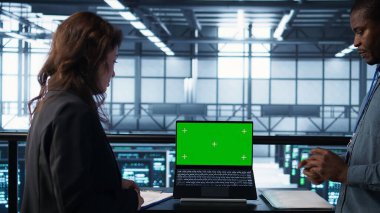 Veri merkezindeki iş arkadaşları yeşil teknolojileri birleştirmek için model dizüstü bilgisayar kullanıyorlar. BT uzmanları sunucu odasında sürdürülebilir enerji çözümleri uygulamak için kroma anahtar defteri kullanıyorlar, kamera B kapat