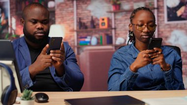 Evde oturan siyah çift cep telefonlarındaki mali raporları analiz ediyor, üretkenlik için çevrimiçi bağımsız işleri yönetmek için takım çalışması yapıyorlar. Genç yetişkinler bağımsızlık kazanıyor. Kamera B.