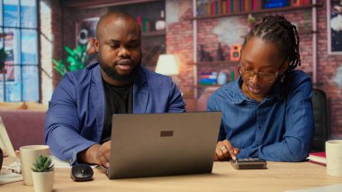 Siyahi bir çift kendi işlerinin mali ve vergilerini yönetiyor. Çatı katlarından uzaktan çalışırlarken masrafları ve gelirleri takip ediyorlar. Borçsuz bir yıl için vergi hesapları yapıyorum. Kamera A.