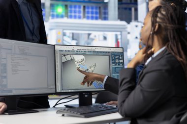 Fotovoltaik fabrika programcısı güneş panellerinin verimliliğini arttırmak için bilgisayarda kodlama yapıyor ve yöneticiye değişiklikler sunuyor. Güneş panelleri imalat fabrikasında çalışan müteahhit, denetçiyle konuşuyor