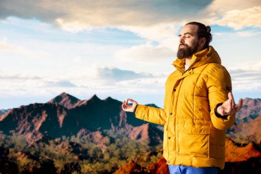 Doğa aşığı gezgin dağın tepesinde meditasyon yapıyor, tepeye başarıyla tırmanıyor ve manzaranın tadını çıkarıyor. Genç sakin zen yolcusu yürüyüş ve meditasyon yapıyor..