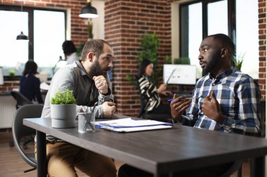 Kafkasyalı başvuru sahibi, işe alım sürecini tartışan Afrikalı Amerikalı askerlere yakından kulak veriyor. İnsan Kaynakları çalışanı beyaz bir erkek adayla görüşüyor, yeni başlayan şirketteki iş olanakları hakkında konuşuyor..