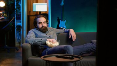Ev sahibi abur cubur yemekten sıkıldı abonelik temelli yayın hizmetleri için TV 'yi kullandı. Kanepede oturan, TV 'de VOD şovlarıyla zaman harcayan, patlamış mısır yiyen, kamera A
