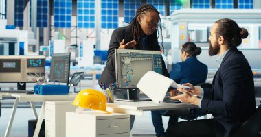 Fotovoltaik fabrika müdürü, güneş pilleri tasarımlarını 3 boyutlu yazılım araçlarıyla görselleştirir, çalışanlarla konuşur. Güneş panelleri fabrika teknisyeni CAD programında bilgisayar simülasyonları yapıyor.