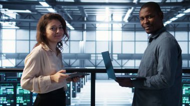 Veri merkezindeki mutlu sistem yöneticilerinin portresi, güvenlik duvarı yapılandırmalarını doğrulayan cihazlar kullanıyor. Jolly takım çalışması bilişim uzmanları sunucu merkezinde ekipman savunmasızlığı taraması yapıyor, kamera B