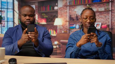 Evde oturan siyah çift cep telefonlarındaki mali raporları analiz ediyor, üretkenlik için çevrimiçi bağımsız işleri yönetmek için takım çalışması yapıyorlar. Genç yetişkinler bağımsızlık kazanıyor. Kamera A.