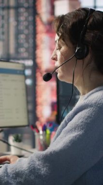 Ofisteki dikey video hesap yöneticisi kulaklık mikrofonuyla konuşuyor, düzenli iletişim yoluyla güçlü müşteri ilişkilerini sürdürüyor. Çalışan müşteriyle konuşuyor, yeni satış olanaklarını tanımlıyor