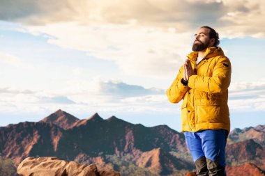 Keyifli bir doğa aşığı dağ sırasının tepesinde meditasyon yapıyor, meditasyon yapıyor ve rahatlık ve zihinsel berraklık için derin nefesler alıyor. Huzurlu zen yürüyüşçüsü tırmanmayı sever.