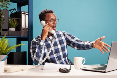 Girişimcinin iş arkadaşından referans olarak laptopunu kullanması şok edici. Şaşırmış yüz ifadesi olan bir adam sabit telefondaki bir çalışanla konuşurken ekranı işaret ediyor..