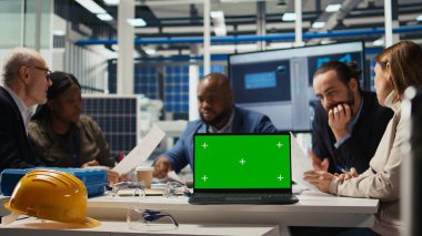 Fabrika mühendisleri kroma anahtar dizüstü bilgisayar kullanarak üretim planlarını rafine ediyorlar. Uzmanlar, izole ekran defteri ve kamera A kullanılarak prototipler için endüstriyel fabrika yapılandırmalarını özetliyorlar.