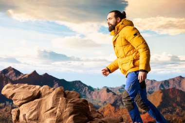 Genç gezgin yüksek rakımlı yabanın, çarpıcı manzaranın ve huzurlu çevrenin tadını çıkarıyor. Doğa aşığı dağın zirvesine tırmanırken mutlu hissediyor kendini..