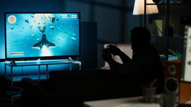 Adam televizyonda çok oyunculu internet oyunları oynayıp konsolunu akıllı televizyona ayarlıyor ve geceleri oyun oynuyor. Nişancı yarışmasında dövüşen oyuncu. Kamera B.