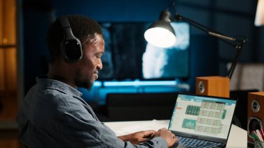 Afrikalı Amerikalı analist dans ederken, ritmi hissederken ve mali dengeyi kontrol ederken muhasebe analizi üzerinde çalışıyor. Uzaktan kumandalı işçi kulaklıkla en sevdiği harika müziği dinliyor. Kamera B.