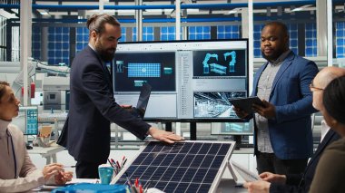 Fabrika yöneticileri yatırımcıların önünde satış yapıyor, üretim hatlarının planlarını gösteriyorlar. Endüstriyel fabrika yapılandırmalarını hissedarlara sunan yönetim, kamera A