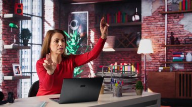 Odaklanmış işçi, ev ofisinden yapay zeka hologramını alıp modern çatı katındaki holografi projeksiyonuna bakıyor. Yapay zeka kullanan bir kadın. Kamera B.