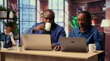 Siyah adam ve kadın rahat dairelerinde oturup dizüstü bilgisayarda dijital pazarlama stratejisini tartışıyorlar. Birbirlerine uzak işlerinde ve serbest yolculuklarında destek oluyorlar. Kamera B.