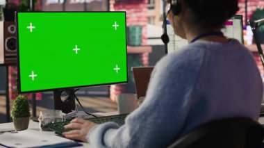 Çağrı merkezi çalışanı yeşil ekran modelleme PC üzerinde çalışıyor, ofiste hesap yönetimi yapıyor. Chroma tuşunun önündeki müşteri destek aracı izole ekran bilgisayarı aramaları, kamera A yakın çekim