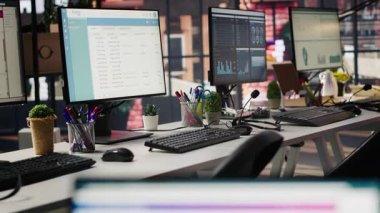 PC boş ofiste analitik gösterge panelleri ve veri grafiklerini gösterir. Dijital veri görselleştirmesini ve işletim yönetimini gösteren ekranları olan ofis çalışma alanı, el kamerası görüntüsü