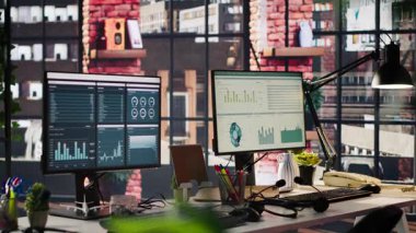Ofis masasındaki bilgisayar monitörleri veri analizlerini ve performans çizelgelerini gösteriyor. Finansal ölçümler ve üretkenlik verilerini gösteren şirket çalışma alanındaki bilgisayar ekranları