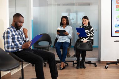 Ofis lobisinde küçük bir grup başvuru sahibi şirketin iç düzenlemelerini okuyor ve iş toplantısına hazırlanıyor. Çok ırklı işsiz insanlar iş görüşmesi için kuyrukta bekliyorlar.