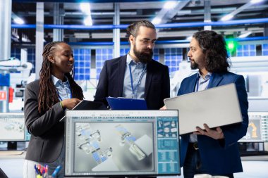 Güneş paneli fabrikasındaki mühendislik ekibi bilgisayar yazılımıyla robot makine ayarlarını ayarlıyor. Ekip çalışması fotovoltaik fabrikası meslektaşları vites performans sorunları teşhis ediyor